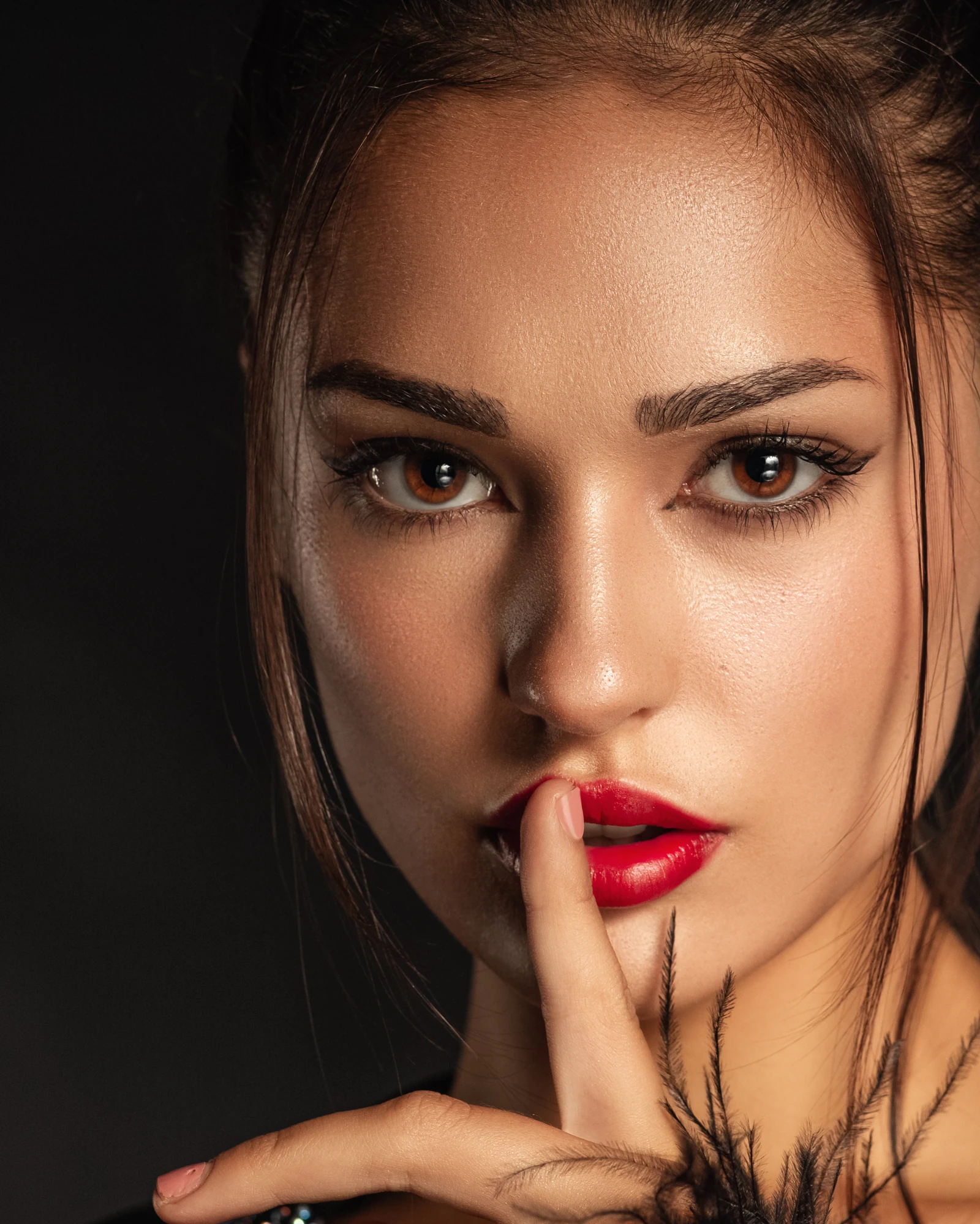 Beauty portrait of a woman with a finger to her red lips