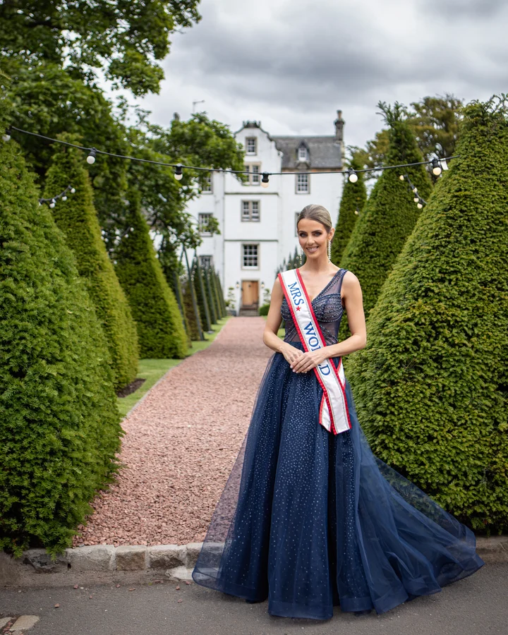 Pageant portrait of a queen in a navy gown in the garden of a Scottish country house